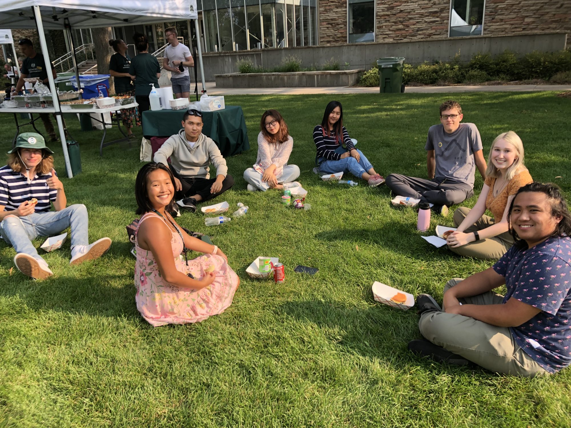 Undergraduate students sitting on grass outside during social