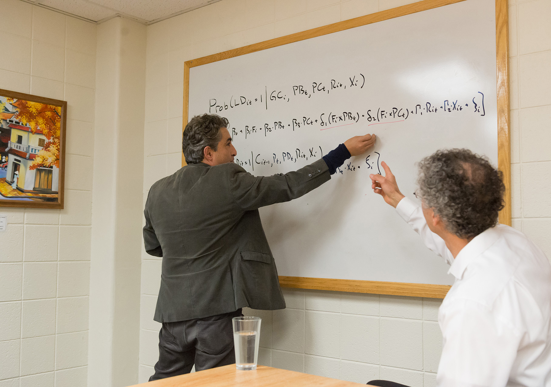 2 professors working on formulas on a white board