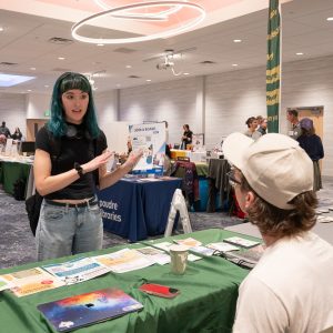 A student talks with a vendor tabling at the democracy summit resource fair